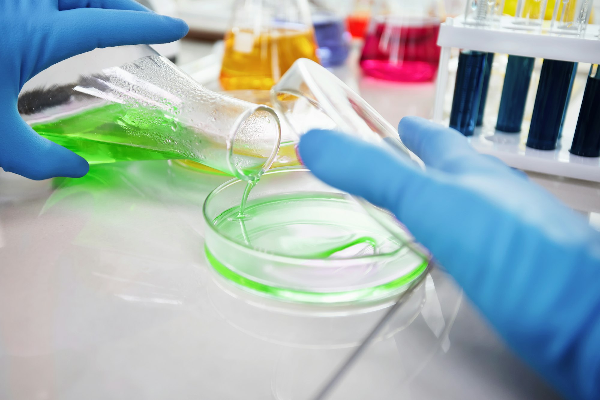 Researcher is dropping the reagent into test tube for reaction testing in chemical laboratory.