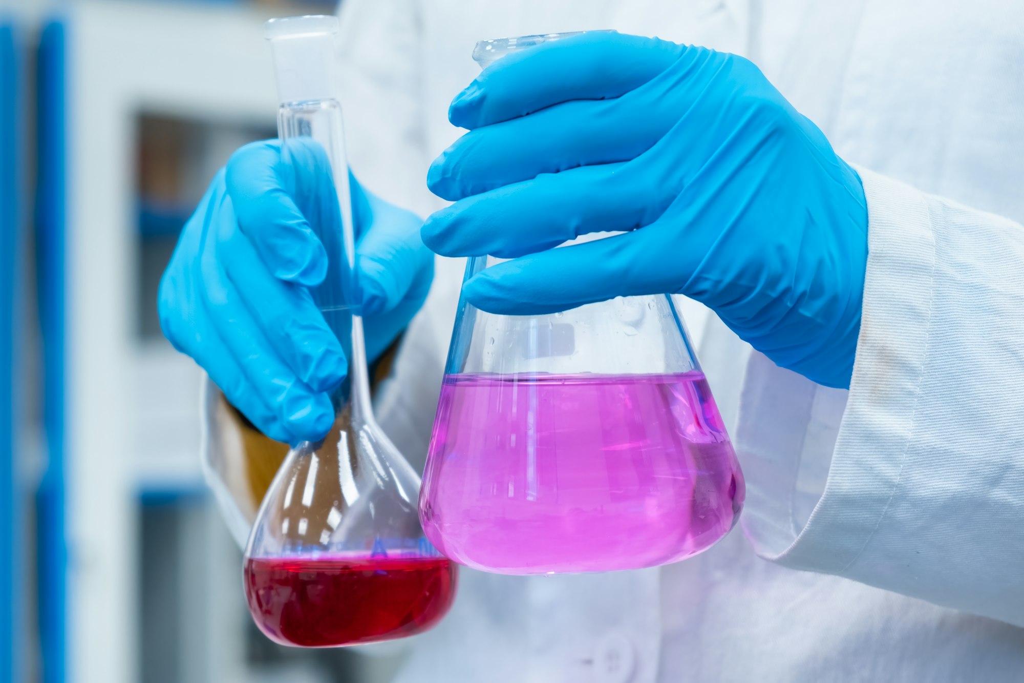 Scientist doing experiments with bright solutions in the flasks at the chemical laboratory